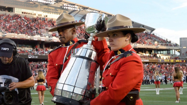 RCMP officers carry the Grey Cup 