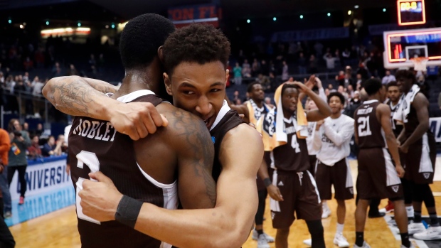 Jaylen Adams, center, hugs Matt Mobley (2) 