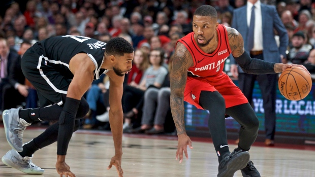 Damian Lillard, right, dribbles around Brooklyn Nets guard Garrett Temple