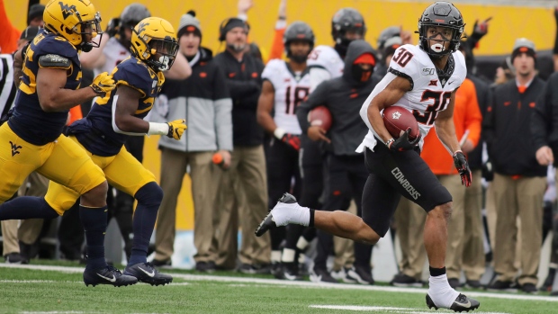 Oklahoma State's Chuba Hubbard eludes West Virginia defenders last Saturday.