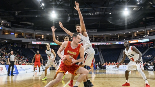 Calgary Dinos' Brett Layton, centre, tries to drive around Carleton Ravens'Eddie Ekiyor