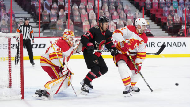 Mark Giordano battles Evgenii Dadonov in front of Jacob Markstrom 