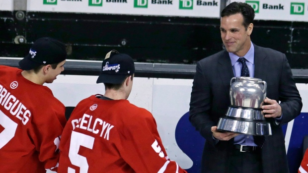 David Quinn hands the Beanpot trophy to Matt Grzelcyk and Evan Rodrigues